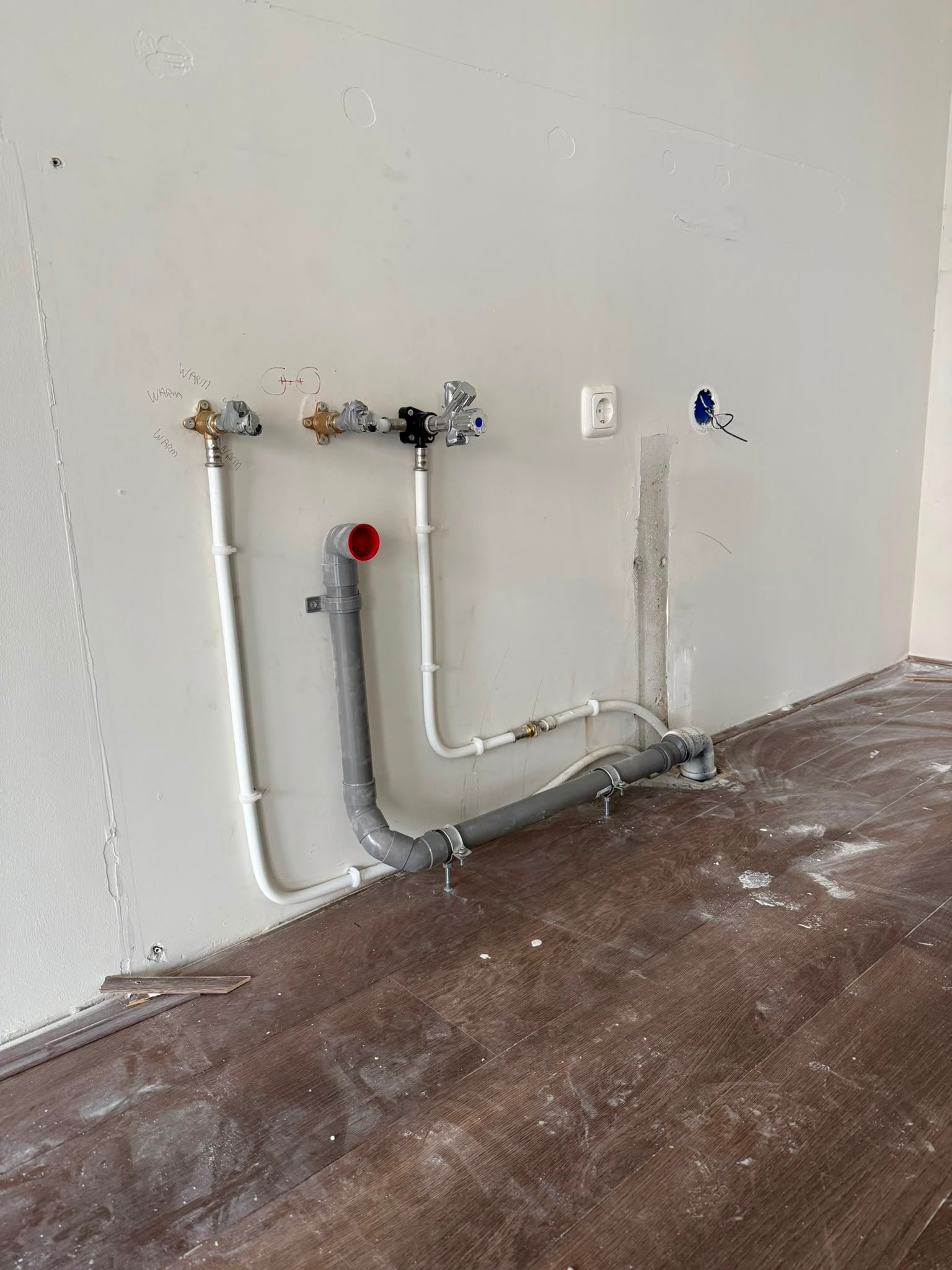 Nieuwe sanitaire waterleidingen en afvoer langs een wand