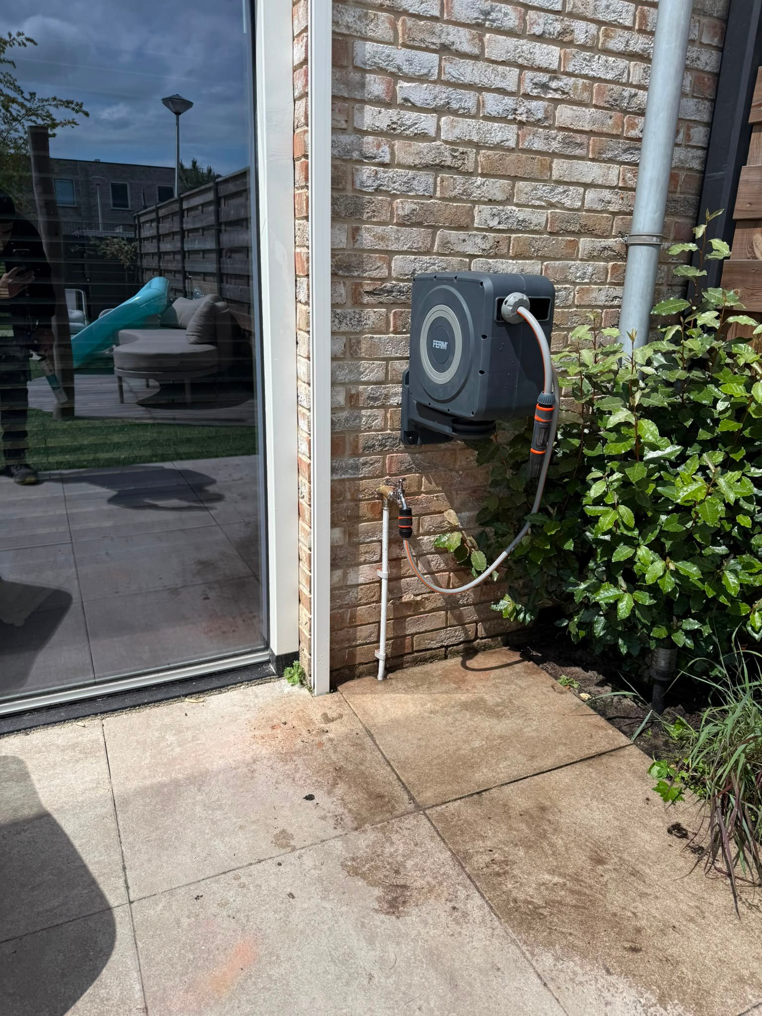 Buitenkraan met gemonteerde tuinslanghaspel aan een gevel
